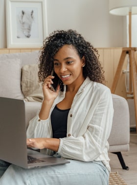 Woman on laptop and talking to customer service over the phone