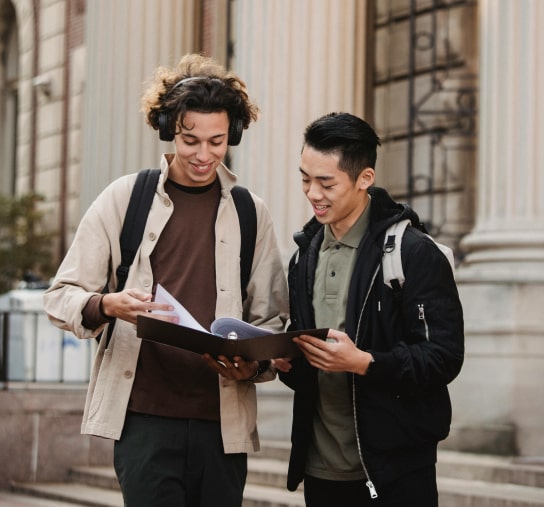 Two young men outside a library looking a school notes